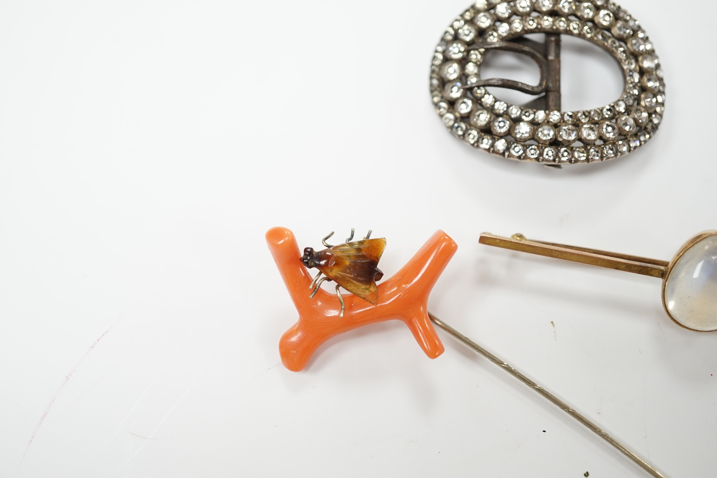 A 9ct and cabochon moonstone set bar brooch, 63mm, a coral and horn set bug stick pin and a paste set buckle.